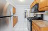 Kitchen with stainless steel appliances, light tile patterned floors, crown molding, light stone counters, and decorative backsplash