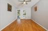 Primary bedroom with a textured ceiling, light finished floors, ceiling fan, and radiator heating unit; door leading out to balcony