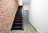 Stairs featuring wood tiled floors, brick wall, and baseboard heating