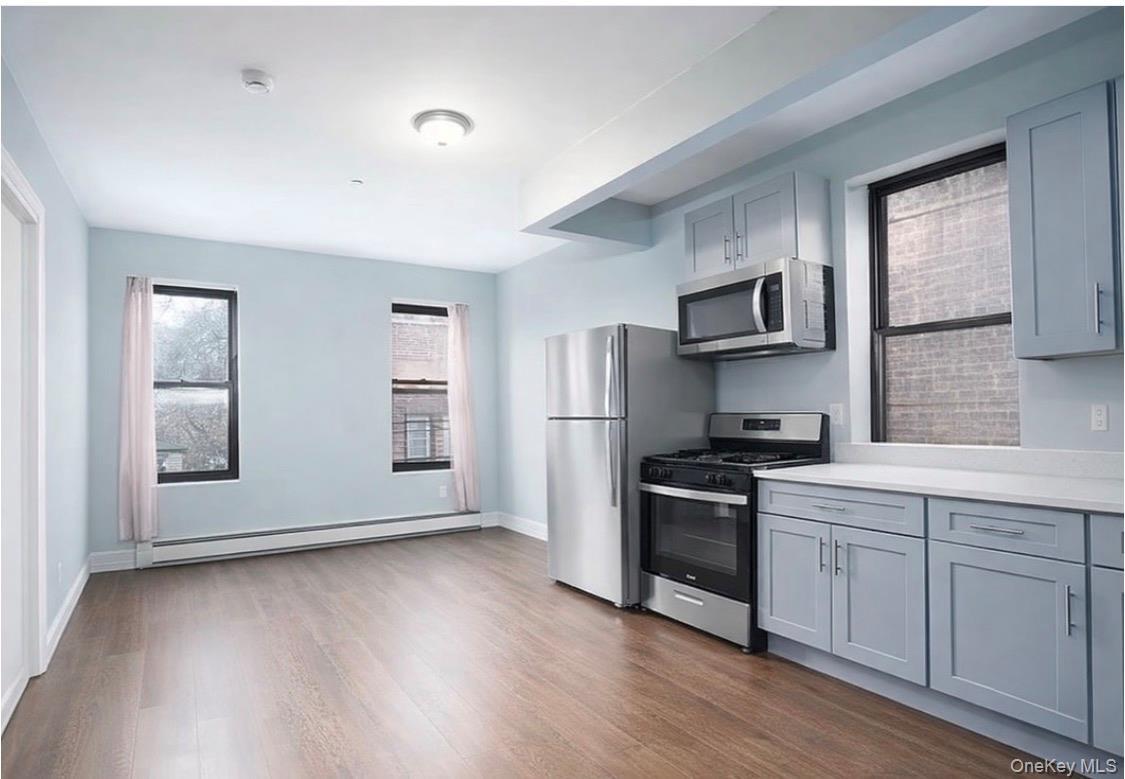 Kitchen with stainless steel appliances, gray cabinetry, and healthy amount of natural light