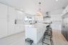 Kitchen featuring wall chimney range hood, premium appliances, a kitchen island, a breakfast bar area, and backsplash