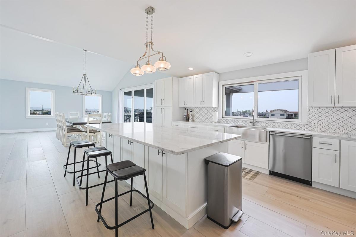 Kitchen with dishwasher, a kitchen bar, healthy amount of natural light, vaulted ceiling, and recessed lighting