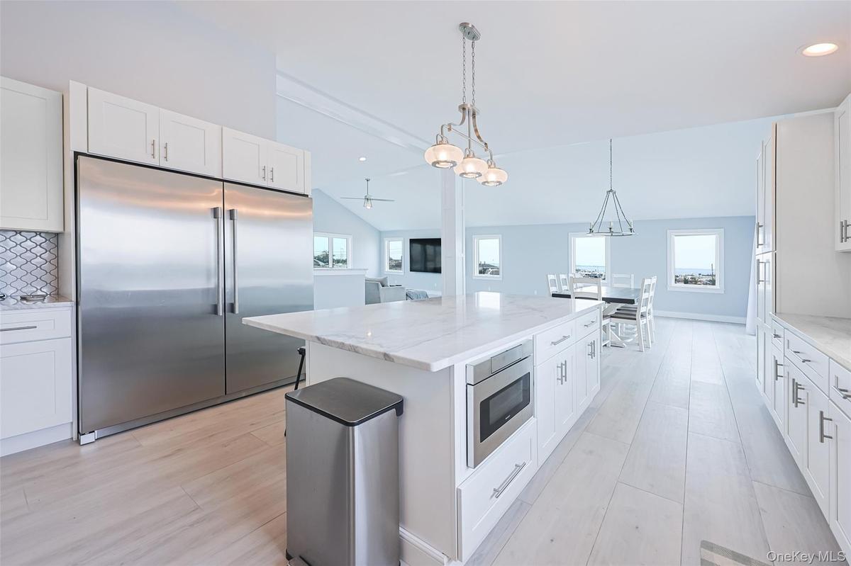 Kitchen with built in appliances, healthy amount of natural light, a center island, light wood-style flooring, and recessed lighting