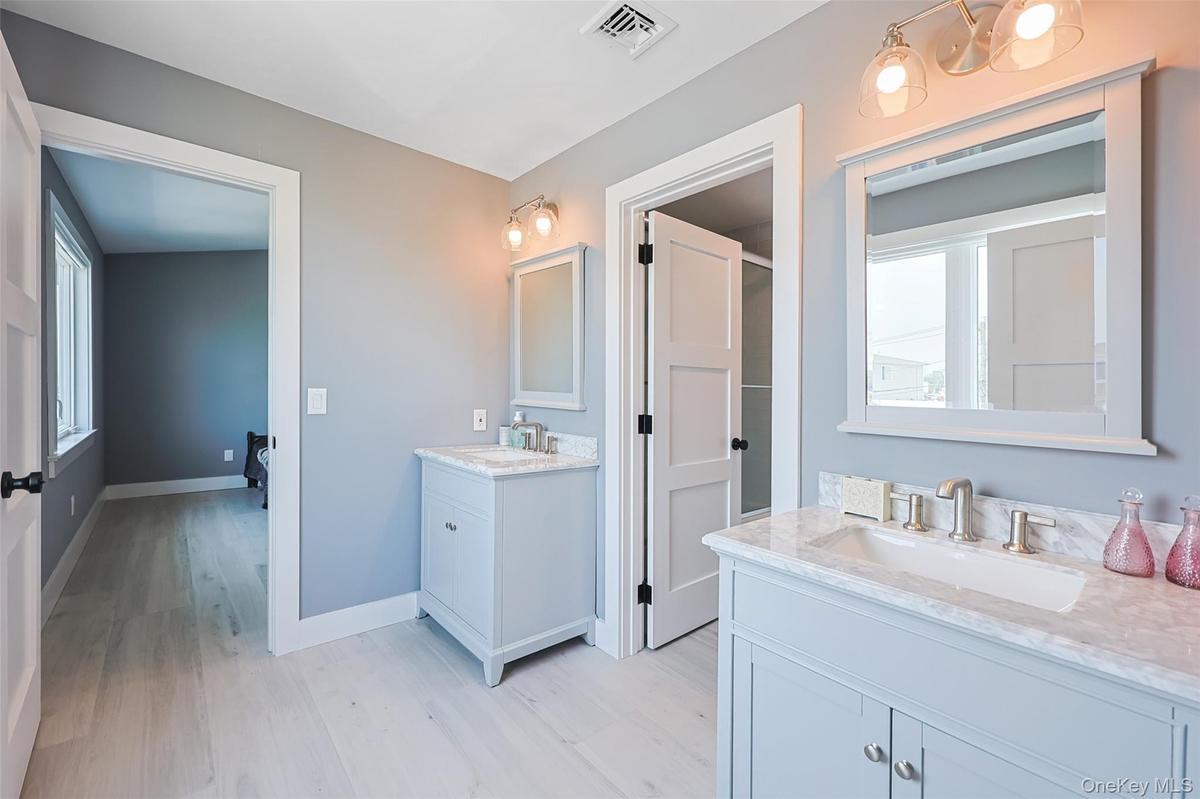 Full bathroom featuring wood finished floors and two vanities