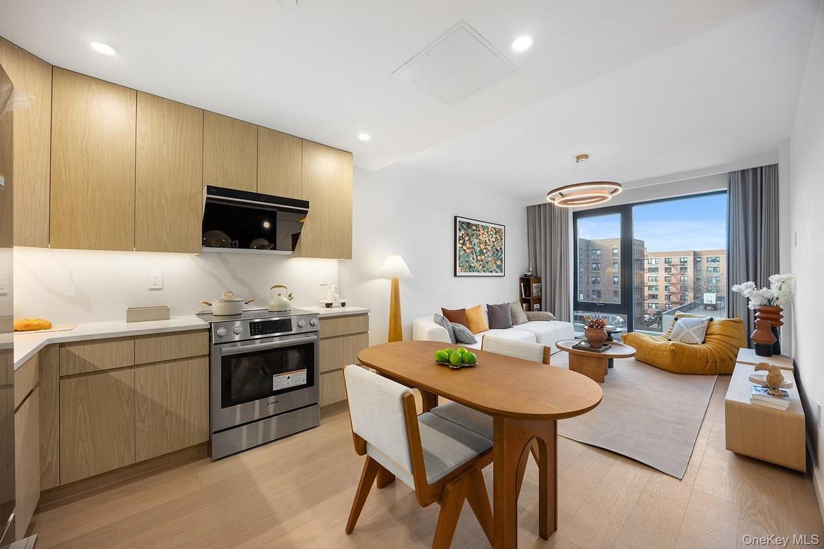 Kitchen with modern cabinets, stainless steel range with electric stovetop, light brown cabinets, light wood finished floors, and ventilation hood