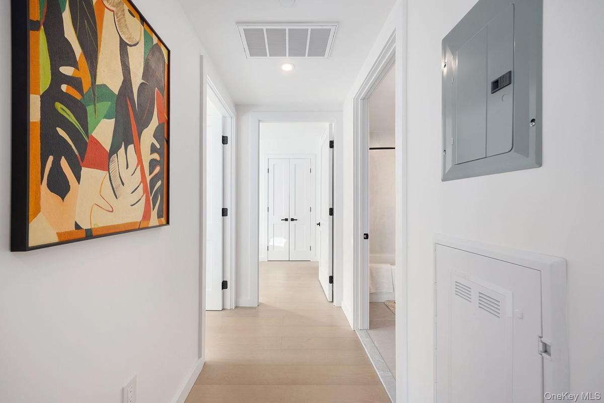 Corridor with electric panel, light wood-type flooring, and recessed lighting