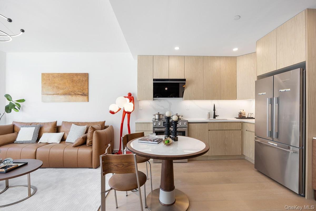 Kitchen with light brown cabinets, modern cabinets, appliances with stainless steel finishes, open floor plan, and decorative backsplash