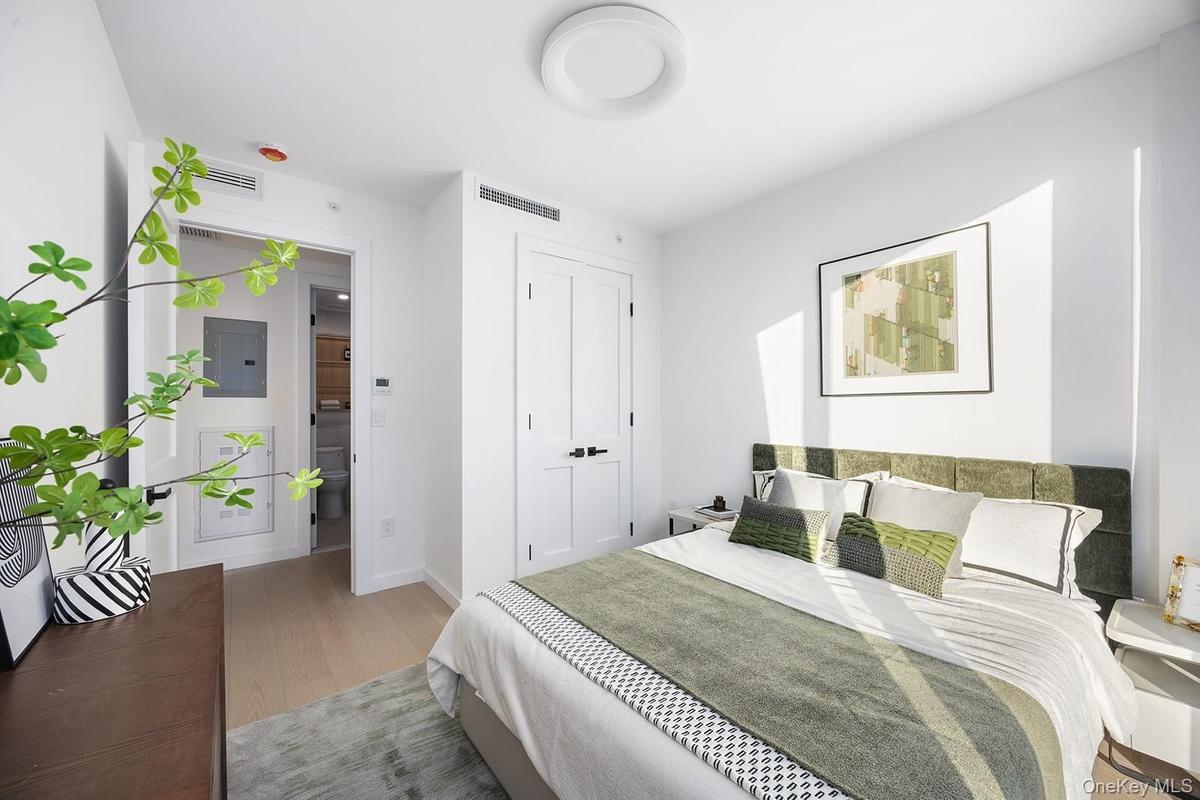 Bedroom with electric panel and light wood-type flooring