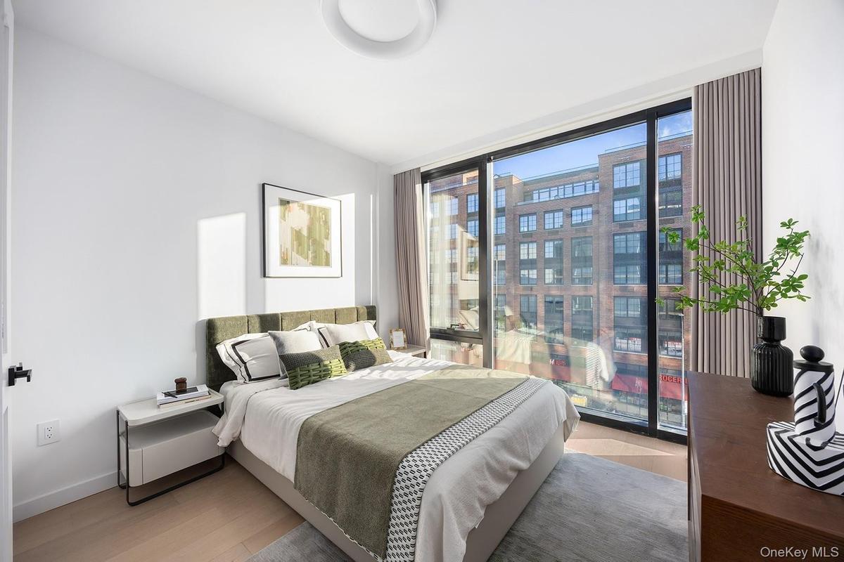 Bedroom with light wood-style floors, floor to ceiling windows, and a city view