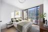 Bedroom with light wood-style floors, floor to ceiling windows, and a city view
