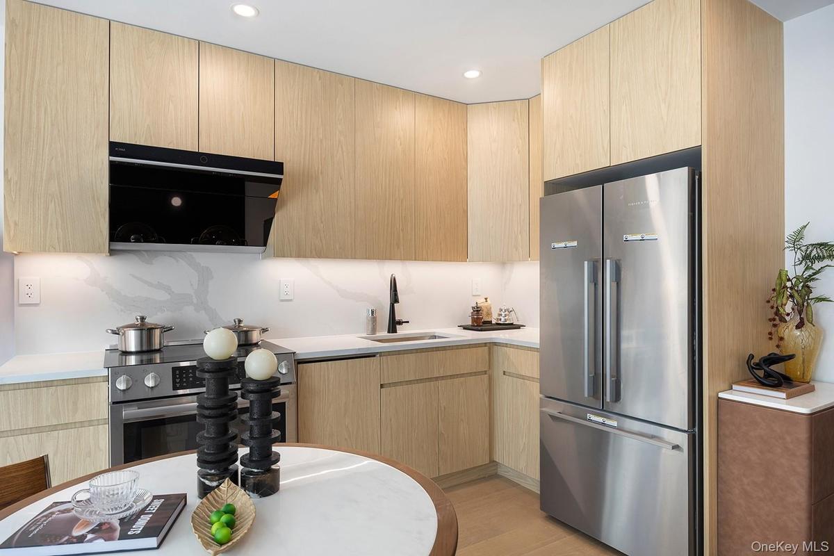 Kitchen featuring light brown cabinetry, modern cabinets, stainless steel appliances, light wood-type flooring, and recessed lighting