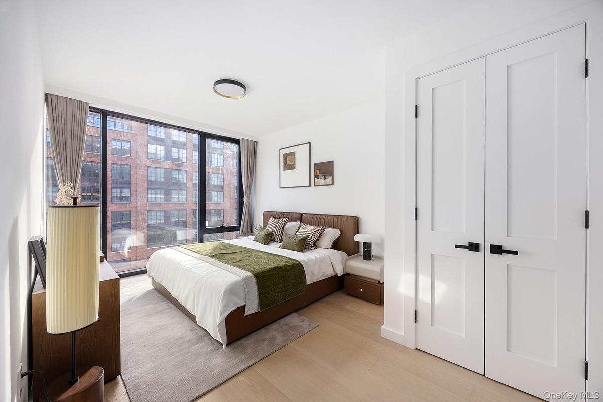 Bedroom featuring wood finished floors, floor to ceiling windows, and a closet