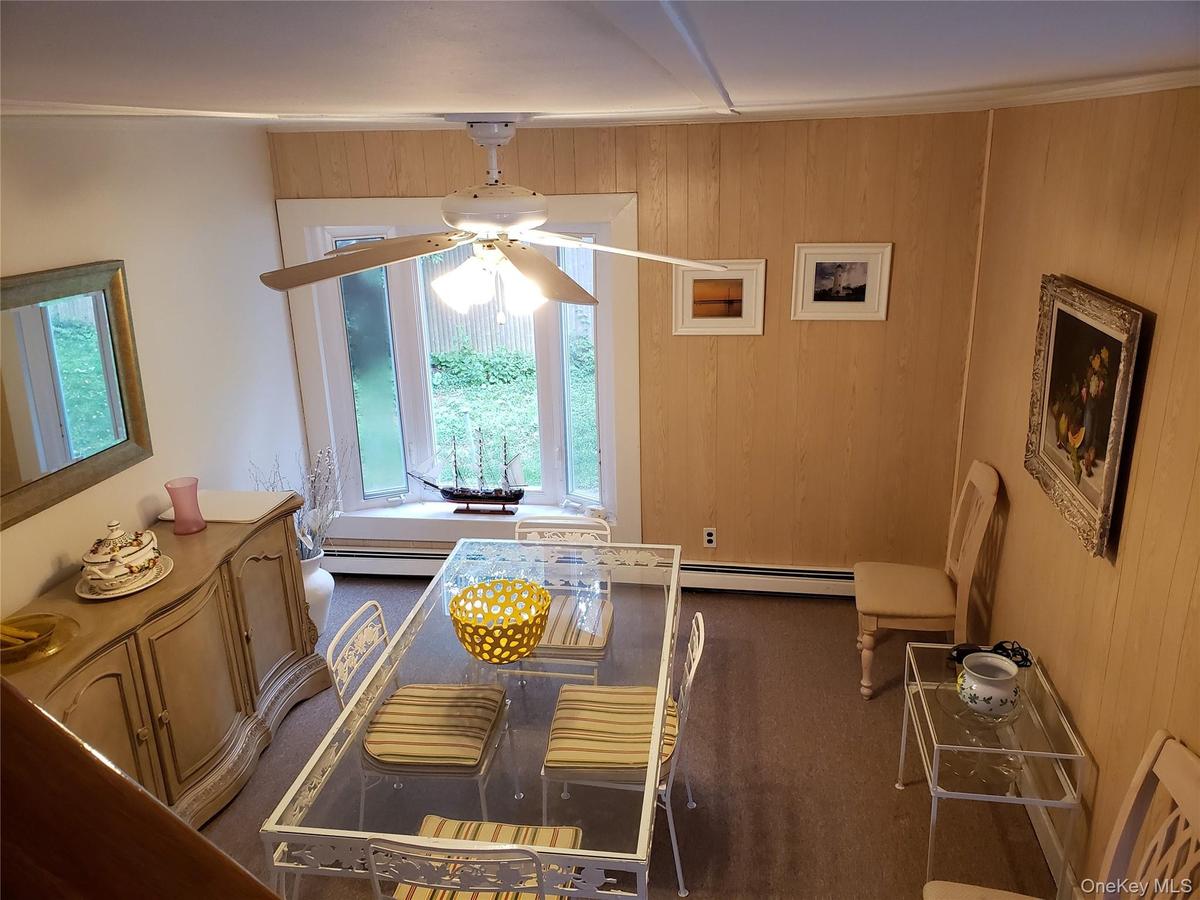 Dining area featuring ceiling fan, wooden walls, and baseboard heating