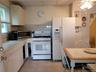 Kitchen with white appliances, a paneled ceiling, a ceiling fan, white cabinetry, and tile counters