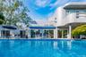 In-ground swimming pool with a tiled edge, multiple sliding glass doors, and a retractable awning