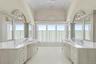 Bathroom featuring a chandelier, two vanities, and high vaulted ceiling