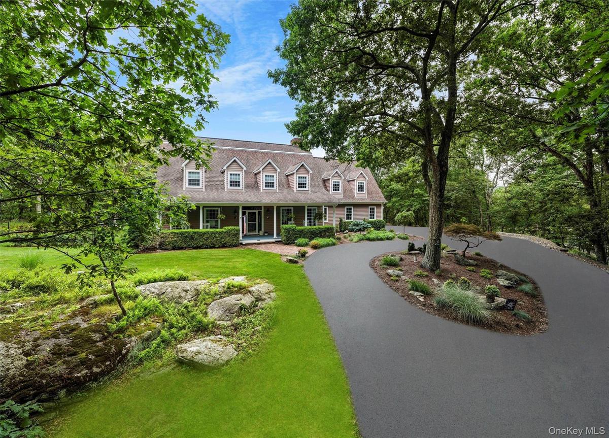 Cape cod-style house with a porch, a front lawn, and curved driveway