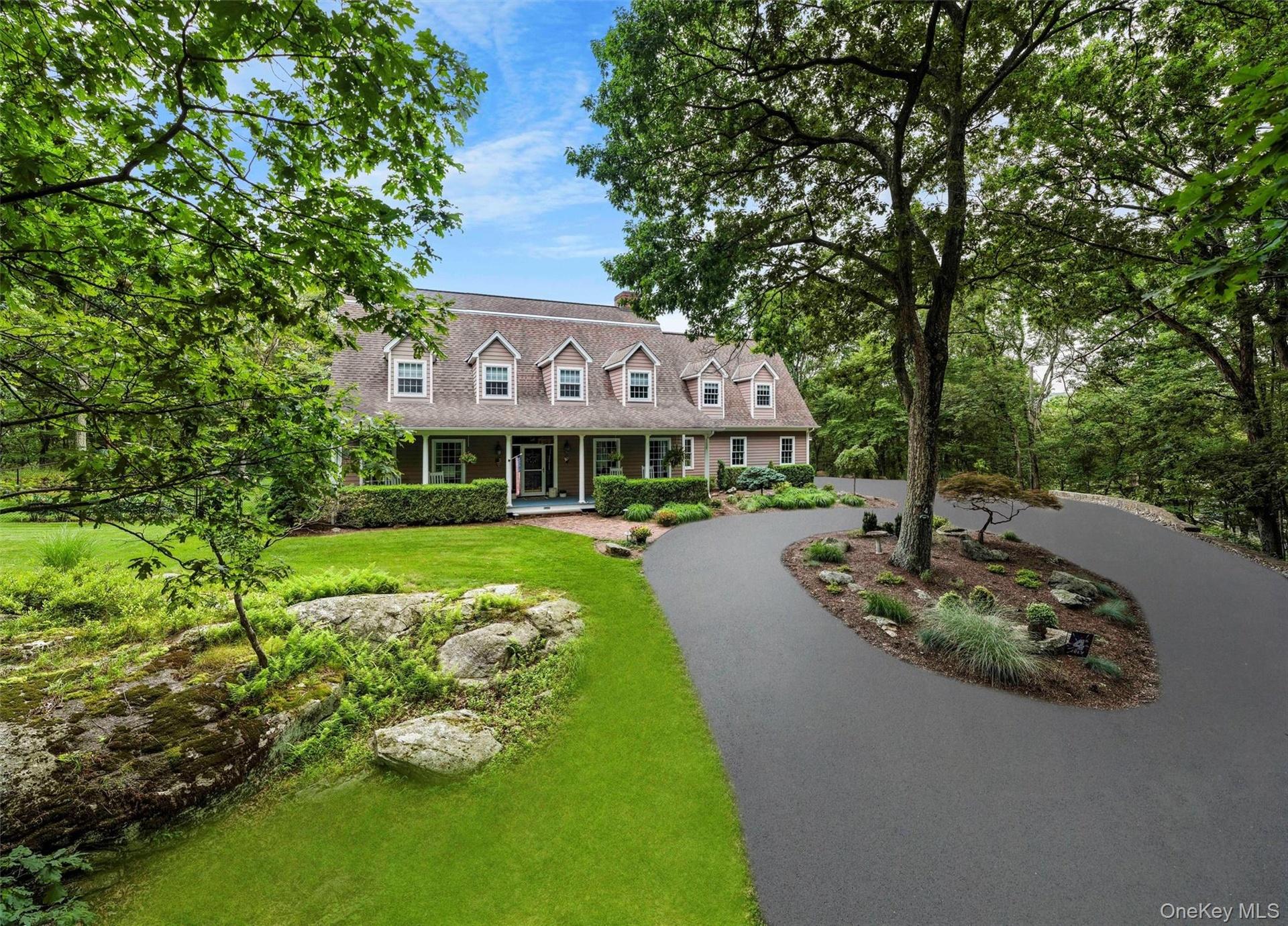 Cape cod-style house with a porch, a front lawn, and curved driveway