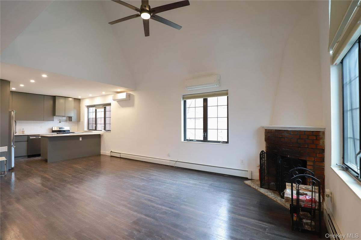 Unfurnished living room featuring baseboard heating, dark wood finished floors, and healthy amount of natural light