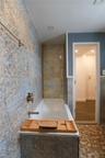 Full bath with a stall shower, vanity, wainscoting, and tile walls. Heated spa-like floors and large bathtub add to spa-like space.