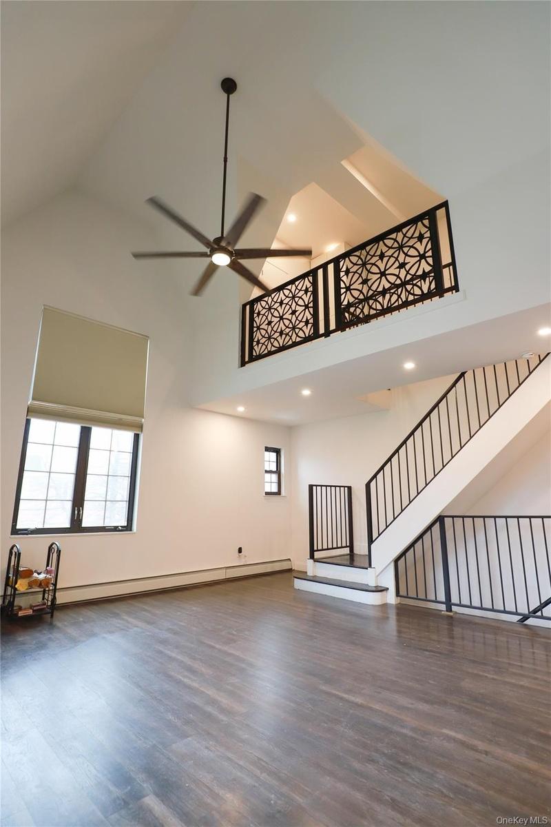Unfurnished living room featuring light wood finished floors, loft-like 2nd floor overlook and high ceilings