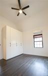Unfurnished bedroom with lofted ceiling, dark wood-style flooring, an AC wall unit, and a ceiling fan. The custom cabinetry is included, with doors cl