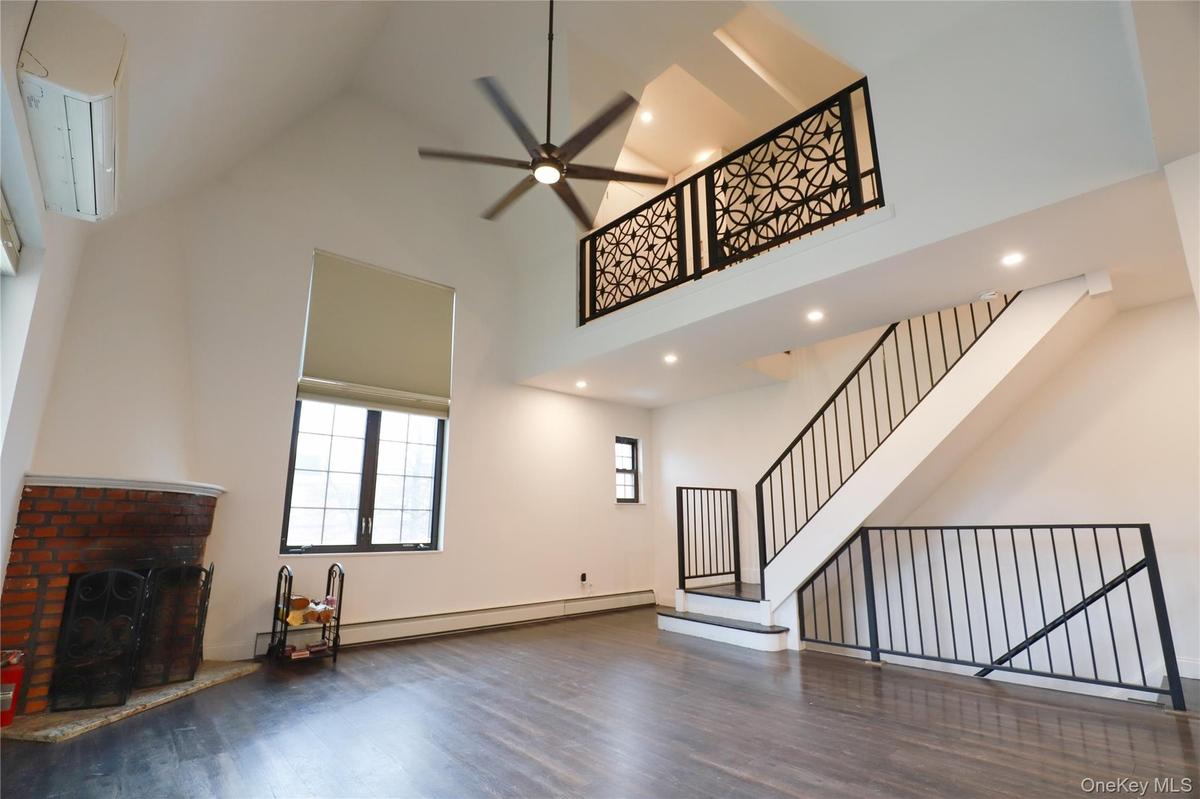 Unfurnished living room featuring light wood finished floors, loft-like 2nd floor overlook and high ceilings