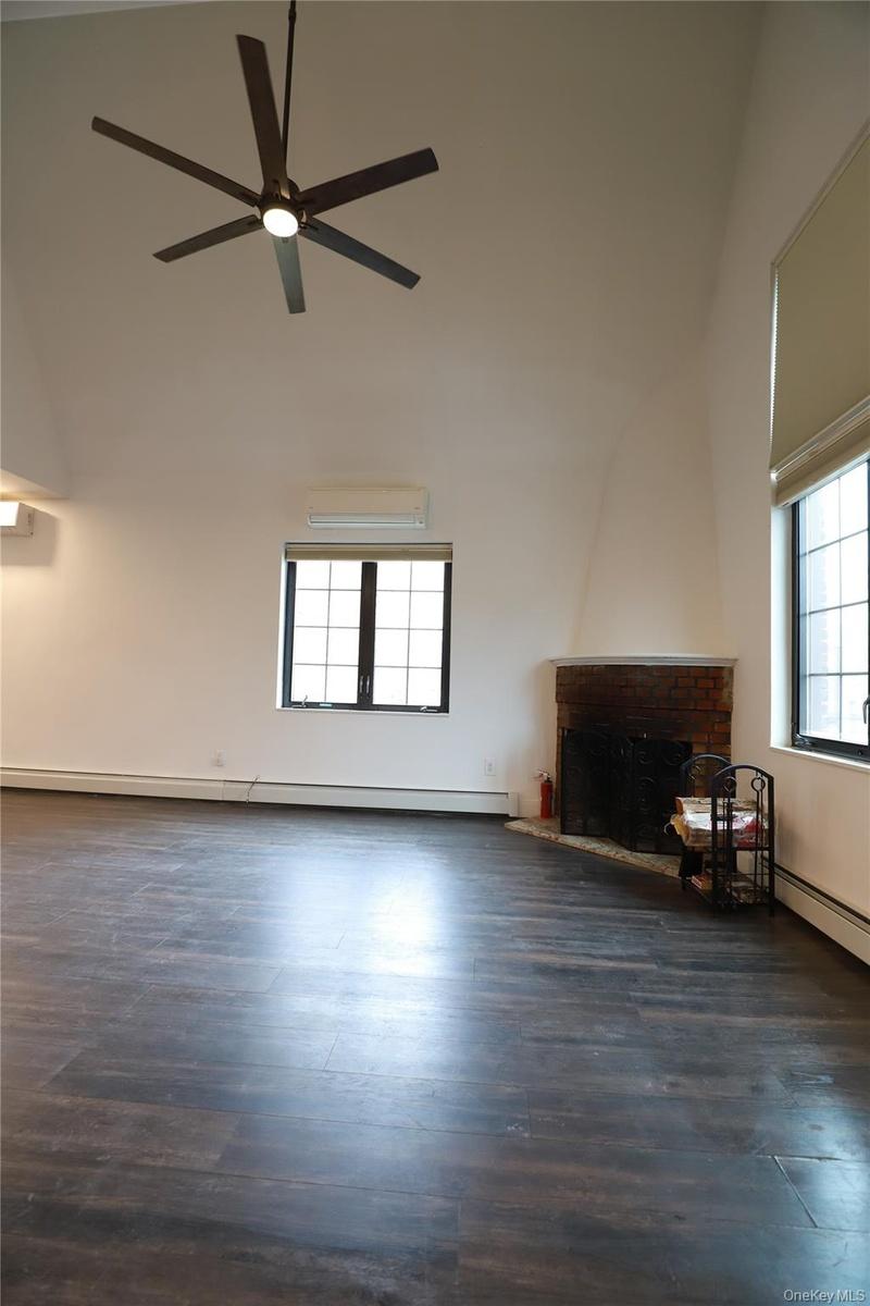 Unfurnished living room featuring baseboard heating, dark wood finished floors, and healthy amount of natural light