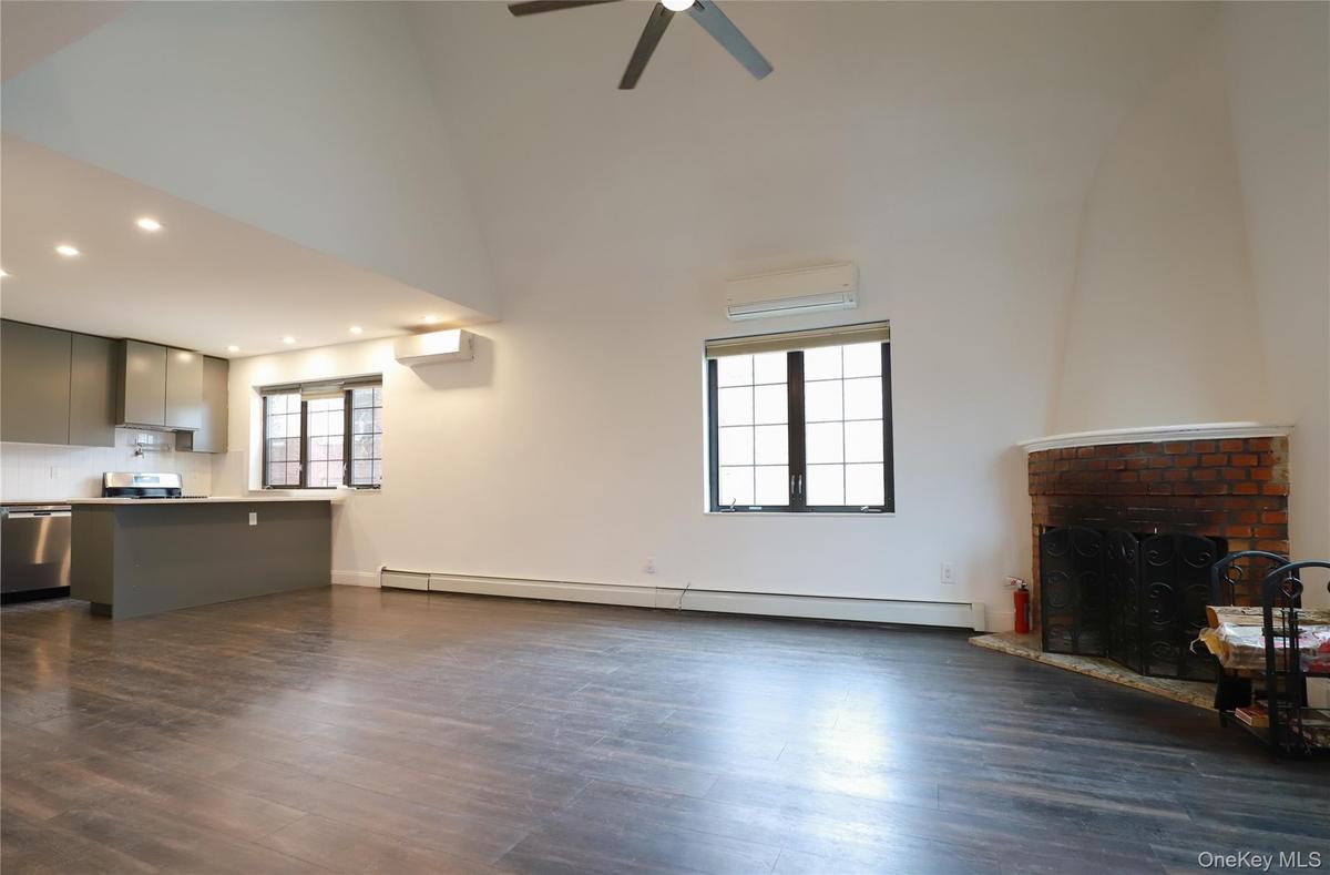 Unfurnished living room featuring baseboard heating, dark wood finished floors, and healthy amount of natural light