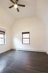 Unfurnished bedroom with lofted ceiling, dark wood-style flooring, an AC wall unit, and a ceiling fan.