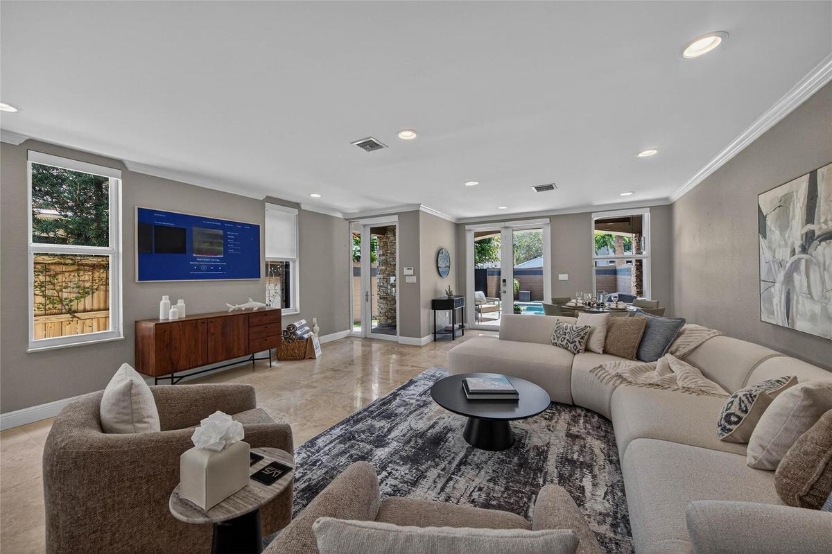 Open layout living room with additional card or dining table overlooking pool area.