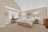 Bedroom with high vaulted ceiling and light colored carpet
