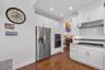 Kitchen featuring backsplash, stainless steel appliances, white cabinets, under cabinet range hood, and dark wood finished floors