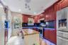 Kitchen featuring reddish brown cabinets, stainless steel appliances, wooden counters, light tile patterned floors, and recessed lighting