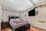 Bedroom featuring electric panel, light wood-style flooring, and a baseboard radiator