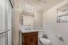 Bathroom with vanity, wainscoting, a shower stall, and tile walls