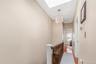 Hallway featuring a skylight, light wood-type flooring, an upstairs landing, and suspended lighting