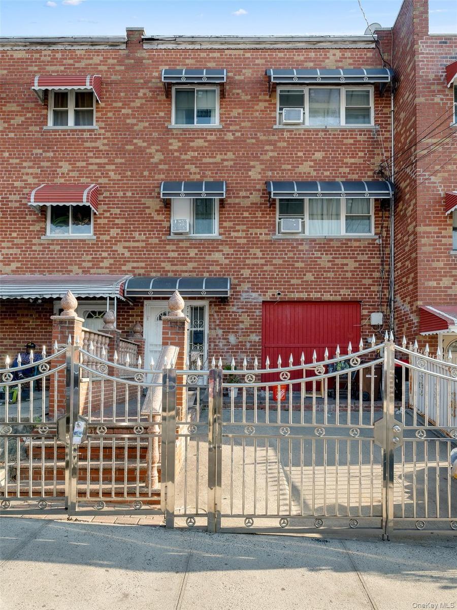 The property features a brick facade with a red garage door and a decorative metal fence