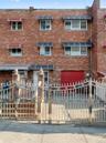 The property features a brick facade with a red garage door and a decorative metal fence