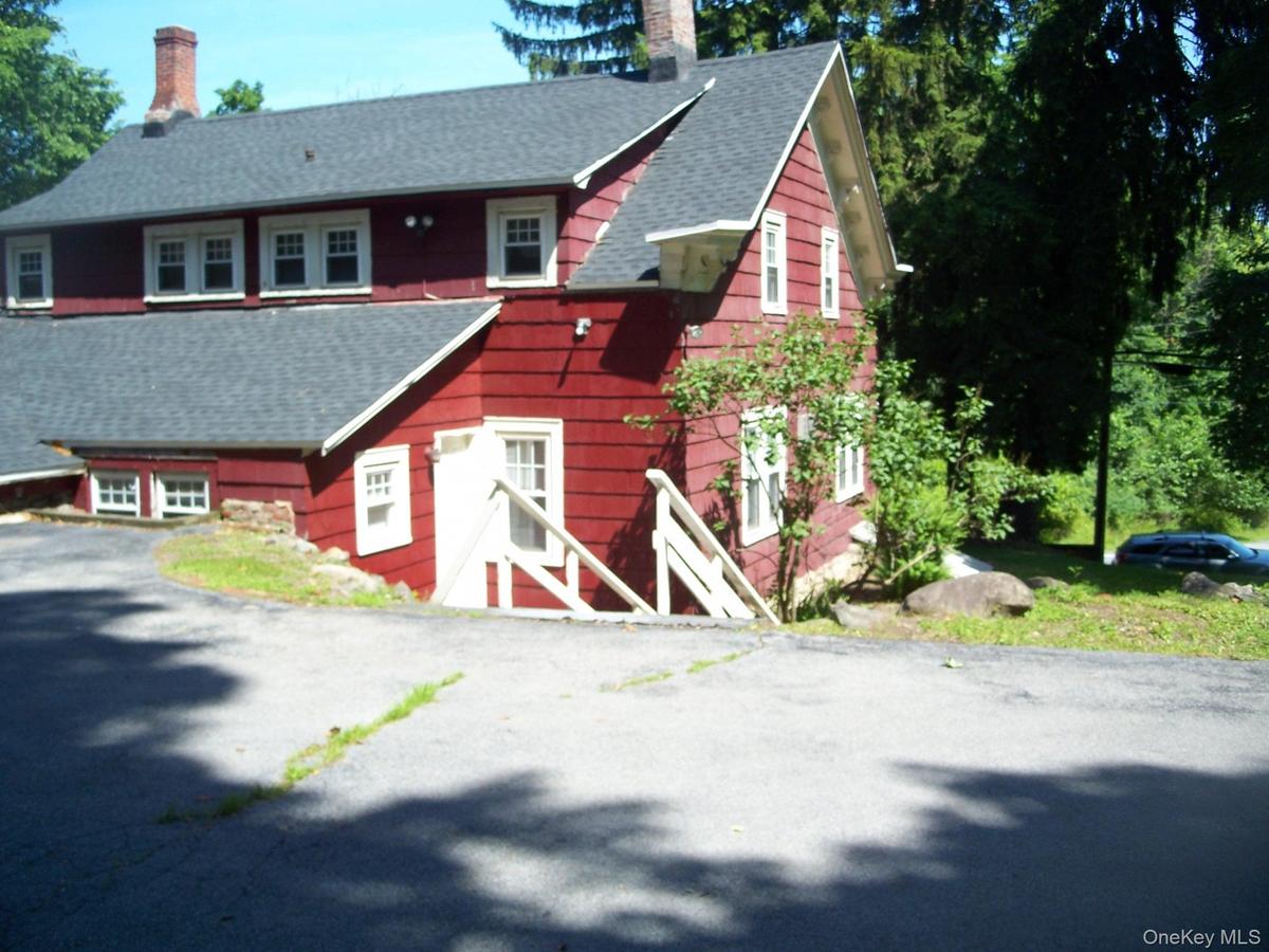 View of front of property featuring a chimney, roof with shingles, and a barn