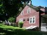 View of property exterior with a chimney and a lawn