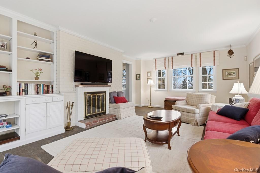 Family room with built in features, ornamental molding, and a brick fireplace