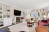 Family room with built in features, ornamental molding, and a brick fireplace