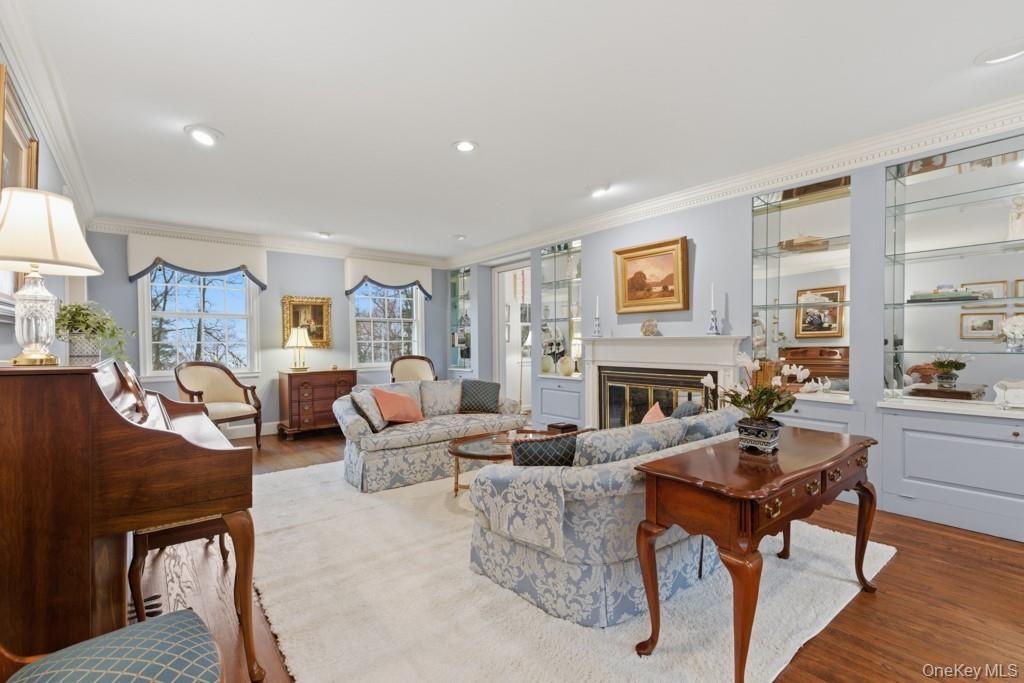 Living room with wood finished floors, ornamental molding,  fireplace, and recessed lighting