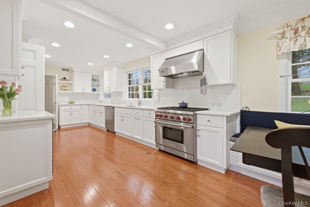 Kitchen featuring stainless steel appliances, white cabinets, light wood-type flooring, open shelves, and breakfast nook.