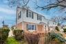 The property features a brick and siding exterior with dark shutters, a front porch with a covered entry, and a fenced yard with established plantings