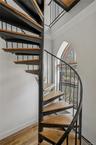 Staircase with wood finished floors, a towering ceiling, and arched walkways