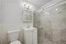 Full bathroom featuring a shower stall, vanity, tile walls, and wainscoting