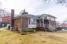 View of front of house with roof mounted solar panels, brick siding, a chimney, and covered porch