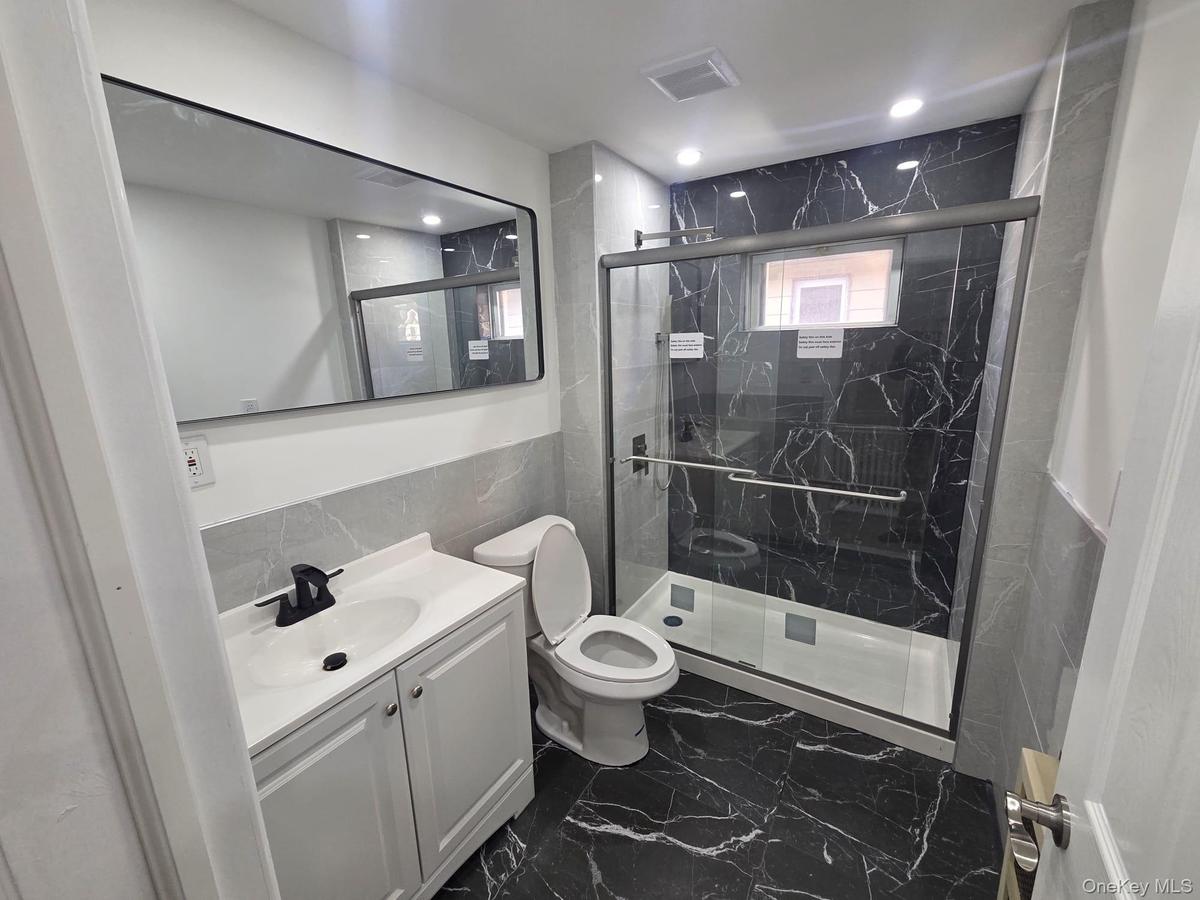 Second Floor Bathroom featuring tile walls, vanity, a tile finish shower, and dark tile finish floors